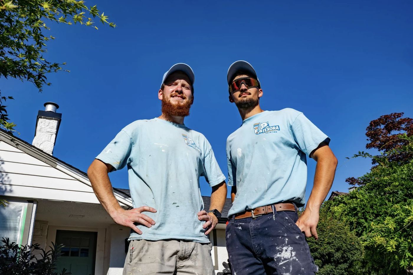 Ruslan and Illia, the two partners who run Texora Painting, in work shirts outside a house